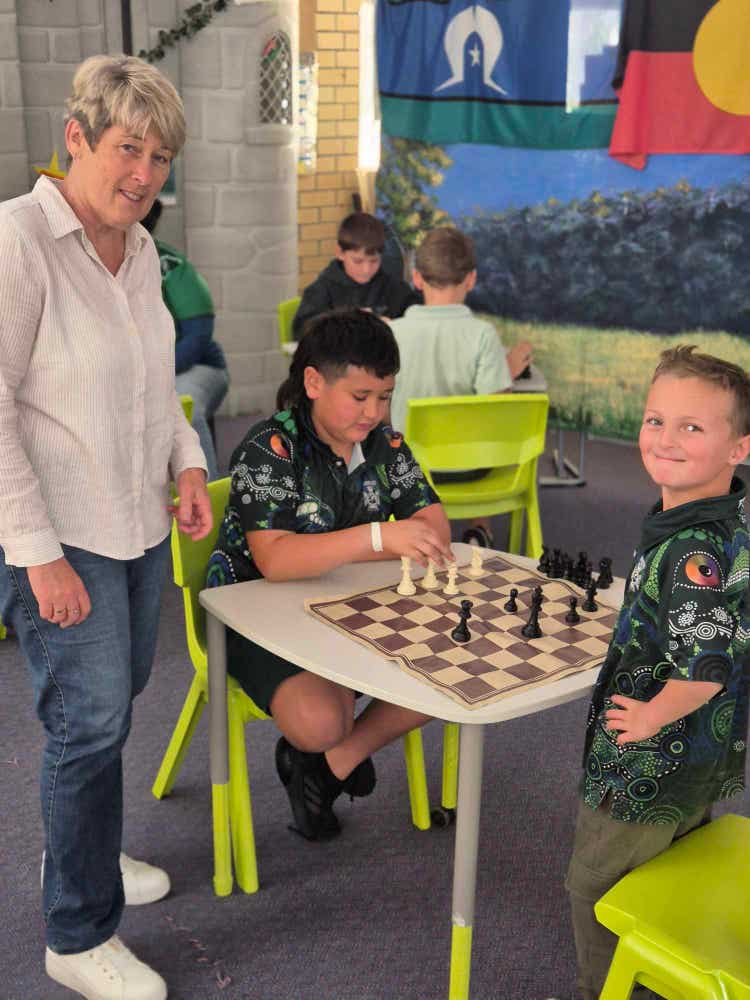 Two students with teacher playing chess